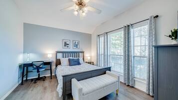 Une chambre à coucher avec un lit, un bureau, une chaise et un ventilateur de plafond.