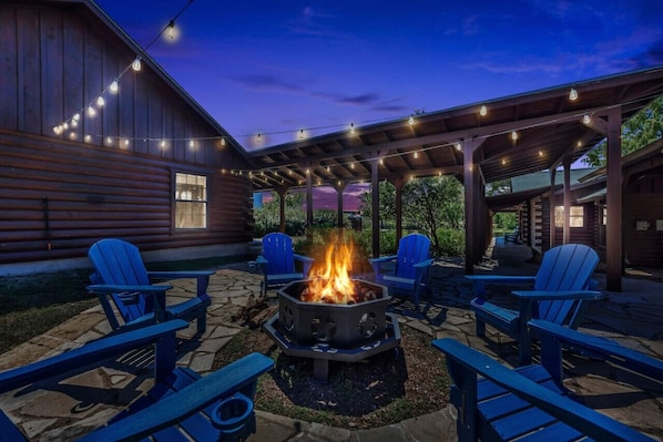 A patio with a fire pit, outdoor seating, and string lights. - NEW! Waterfront property w/ fire pit & corn hole! (Marble Falls)