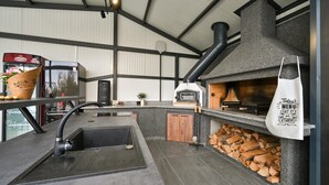 Une cuisine professionnelle équipée d’un four à bois, d’une machine à café et d’une poubelle.