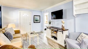 A living room with a sofa, a coffee table, a TV, and a fireplace. - North Myrtle Getaway, 2bd 2ba bottom unit in 3unit building 1-block from beach (North Myrtle Beach)