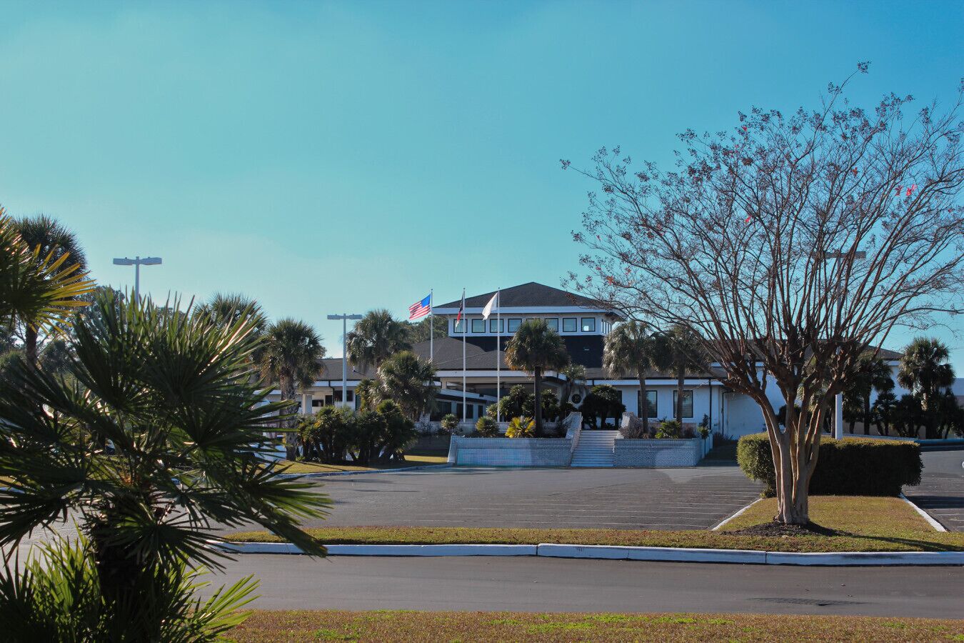 A two-story hotel with a flag, palm trees, and a parking lot.