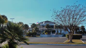 A two-story hotel with a flag, palm trees, and a parking lot.