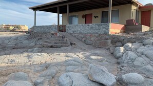 A beach house with a stone facade, a covered patio, and a staircase leading to the entrance.