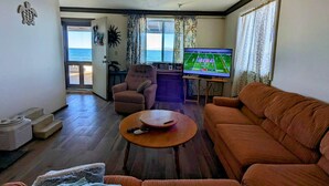 A living room with a sofa, armchair, and a television displaying a sports game.