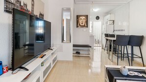 A modern living room with a flat-screen TV, a Buddha statue, and a dining area with bar stools. - Vacation home Hamber by Interhome (Puerto de Mazarrón)