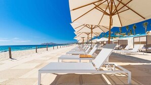 A beach with rows of sun loungers and umbrellas, a clear blue sky, and the ocean in the background. - Luxurious Beachfront Resort Villa La Valencia Studio unit. Great views & dining. (San José del Cabo)