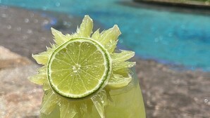 A cocktail with a lime garnish in a glass, placed on a stone surface near a pool. - Luxurious Beachfront Resort Villa La Valencia Studio unit. Great views & dining. (San José del Cabo)
