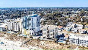 A high-rise hotel with multiple floors, a parking area, and a beach view. - A Walk From the Beach, 2bed 2bath apartment in 3unit building 1 block from Ocean (North Myrtle Beach)