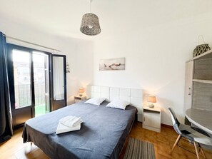 Una camera da letto con un letto, abat-jour, una sedia, una scrivania e vista sull'esterno.
