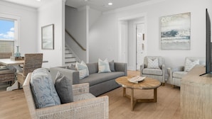 Una sala de estar moderna con un sofá gris, sillones de mimbre, una mesa de centro de madera y un ventilador de techo.