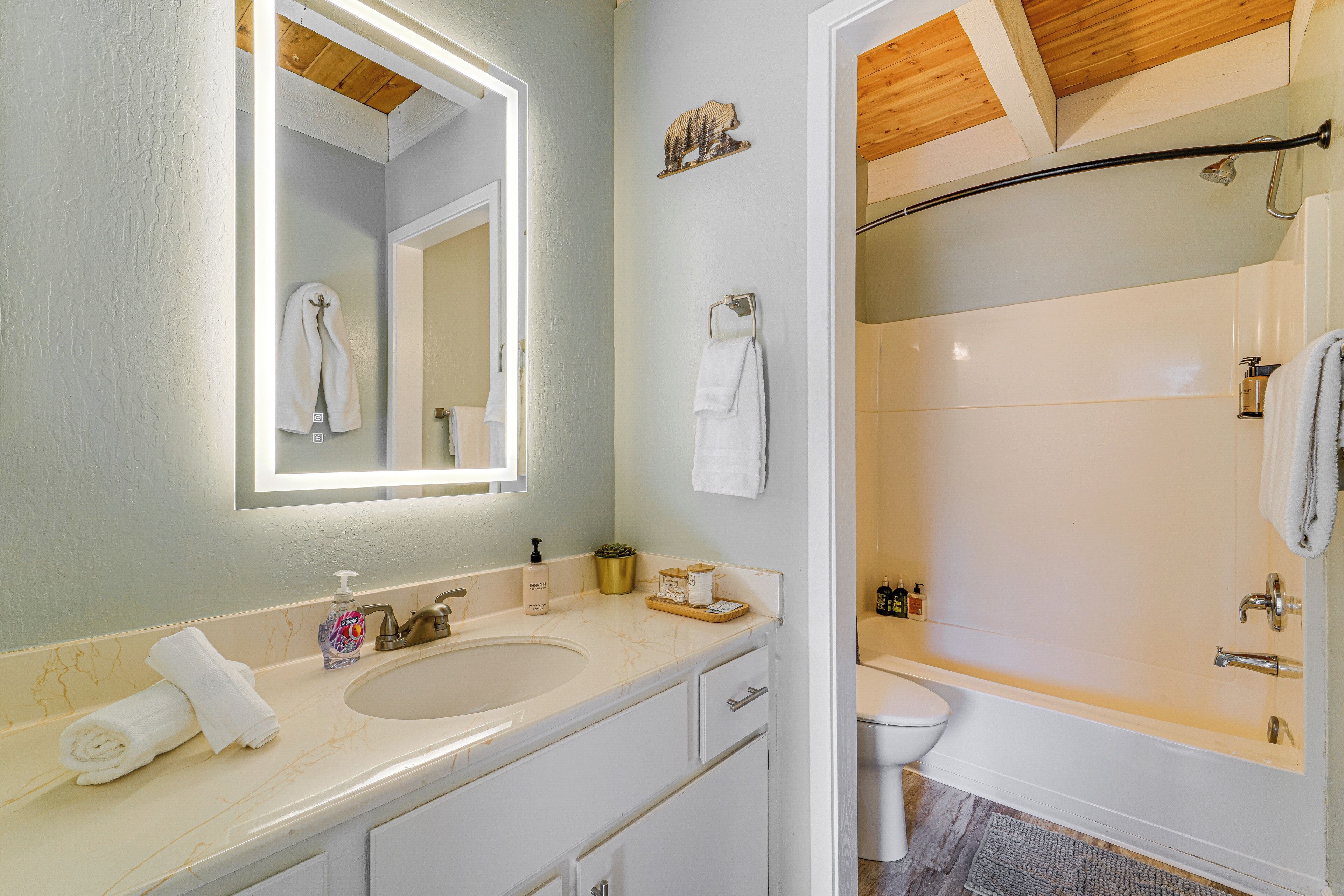 A bathroom with a sink, mirror, towel rack, and a shower area.