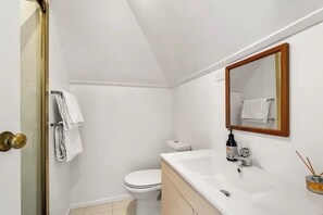 A bathroom with a toilet, sink, and a mirror. - Parnell Self-Contained Cottage
(Auckland)
