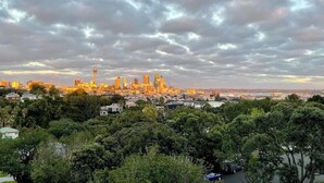 A city skyline with a prominent tower, surrounded by dense greenery and a cloudy sky. - Parnell Self-Contained Cottage

 (Auckland)