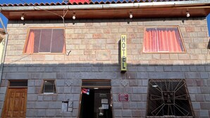 Facciata di un hotel con un'insegna 'HOTEL', una porta in legno e una finestra con inferriata metallica.
