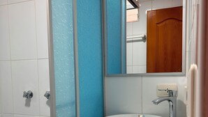 Un bagno con un lavandino bianco, uno specchio e una doccia.