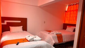 Una camera d'albergo con due letti, ognuno con piumone e cuscini bianchi, e una parete decorata di rosso.