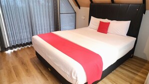 Une chambre à coucher avec un grand lit, une couvre-lit rouge et blanche et un plancher en bois.
