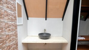 Une petite salle de bain avec un lavabo en pierre, un plancher en bois et un mur en briques.