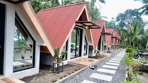 Une rangée de chalets modernes de style A, dotés de grandes fenêtres, d’un chemin de gravier et de plantes en pot.