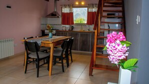 A kitchen with a dining table, chairs, a wooden ladder, and a potted plant. - cabañas del sauce (El Hoyo)