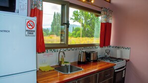 A compact kitchen with a sink, stove, and microwave. - cabañas del sauce (El Hoyo)