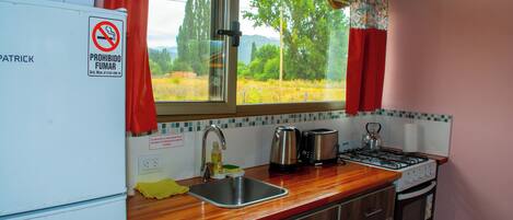 A compact kitchen with a sink, stove, and microwave.