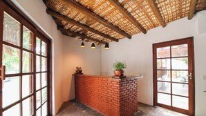 A reception area with a brick counter, potted plants, and a ceiling with a woven pattern. - AROEIRA POUSADA TRANCOSO (Porto Seguro)