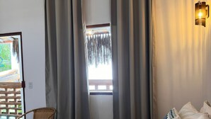 A bedroom with a bed, pillows, a chair, and a view of the outside. - AROEIRA POUSADA TRANCOSO (Porto Seguro)