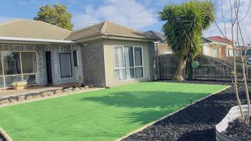 Stunning home with a modern design, large windows, and a lawn with a palm tree.