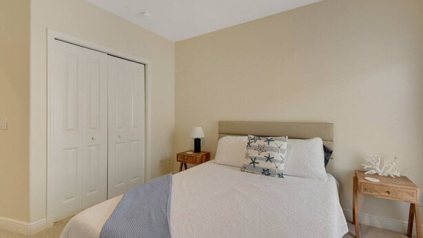 A bedroom with a bed, bedside tables, a nightstand, a lamp, and a decorative item.