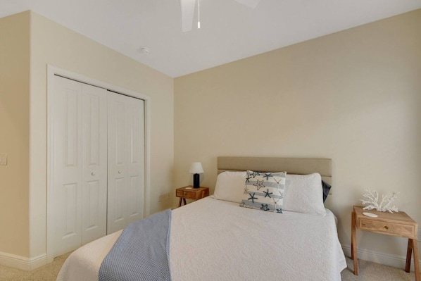 A bedroom with a bed, bedside tables, a nightstand, a lamp, and a decorative item.