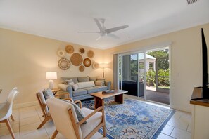 A living room with a sofa, chairs, a coffee table, a lamp, and a ceiling fan. - Ocean Reef 101 - Ocean Bliss (St Augustine Beach)