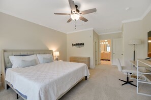 A bedroom with a bed, bedside tables, a desk, and a ceiling fan. - Ocean Reef 101 - Ocean Bliss (St Augustine Beach)
