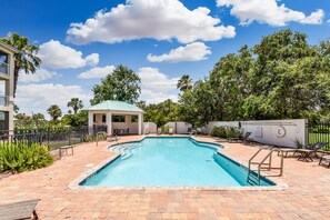 A swimming pool with a gazebo, lounge chairs, and a fenced area with palm trees. - Ocean Reef 101 - Ocean Bliss (St Augustine Beach)