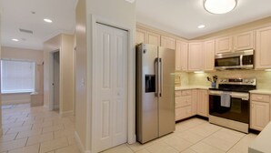A kitchen with light-colored cabinets, a stainless steel refrigerator, a microwave, and an oven.