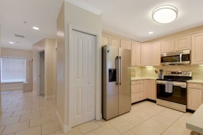 A kitchen with light-colored cabinets, a stainless steel refrigerator, a microwave, and an oven.
