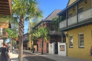 A street with buildings, palm trees, and a person walking.