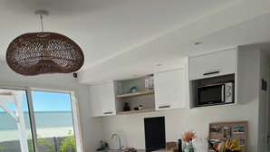 Une cuisine moderne avec des meubles blancs, un micro-ondes noir et un coin repas avec des chaises bleues.