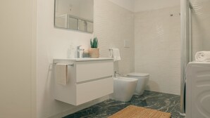 A modern bathroom with a white vanity, a mirror, a bidet, and a shower area. - Diana - MyHomeinComo (Como)