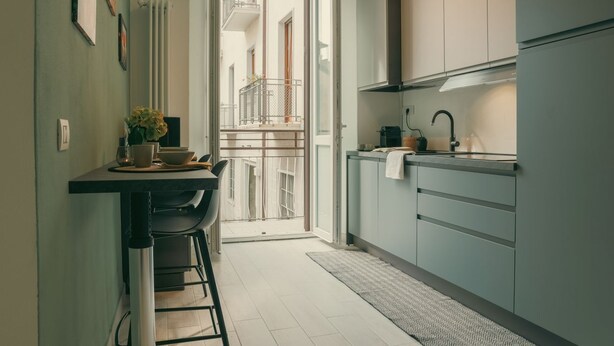A narrow kitchen with a dining area, a view to a balcony, and a radiator on the wall. - Diana - MyHomeinComo (Como)