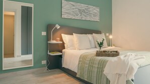 A bedroom with a bed, bedside tables, a nightstand, a wall-mounted lamp, a framed picture, and a door. - Diana - MyHomeinComo (Como)