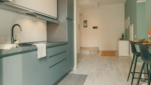 A modern kitchen with a built-in stove, a sink, and a dining area with a table and chairs. - Diana - MyHomeinComo (Como)