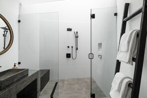 A modern bathroom with a glass-enclosed shower, a marble sink, and a towel rack.