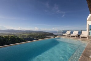 A modern infinity pool with a clear view of the ocean and distant landscape.