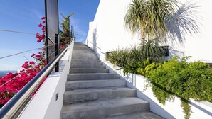 A staircase leading up to a white building with a metal railing, surrounded by greenery and pink flowers. - Adults Only! Desecheo Suite II at Ocaso Luxury Villas (Rincon)