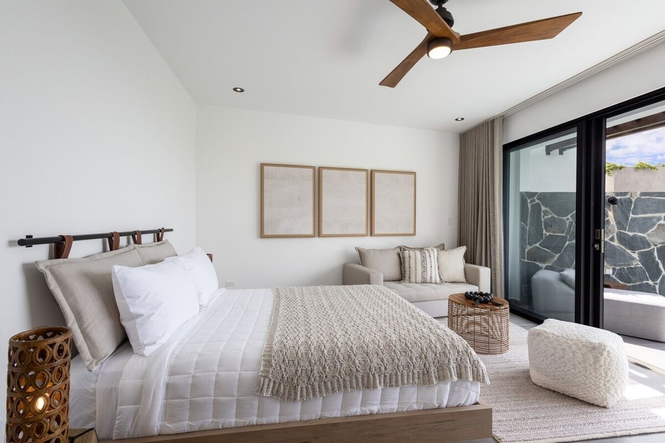 Une chambre moderne avec un lit, un canapé et une porte vitrée donnant sur un balcon.
