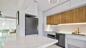 A modern kitchen with white marble countertops, stainless steel appliances, and wooden cabinetry.