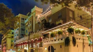 A multi-story building with balconies, string lights, and a gated entrance.