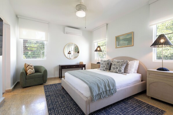 Quarto com cama, cadeira, escrivaninha, luminária e janela.