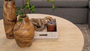 A round wooden table with two wooden vases and a tray with decorative items. - Villa Georgetti Hidden Gem in Miramar, SJ | Power Generator, Water Cistern, Parking (San Juan)